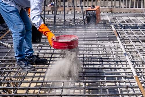 Hand of worker sprinkling chemical of Crystalline wareproofing before pour concrete slab for Structural Crystalline waterproofing system at site construction