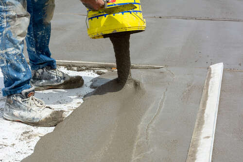 Worker Spreading Building Screed on a Floor of a House during Energy Redevelopment Work on Blurred Background
