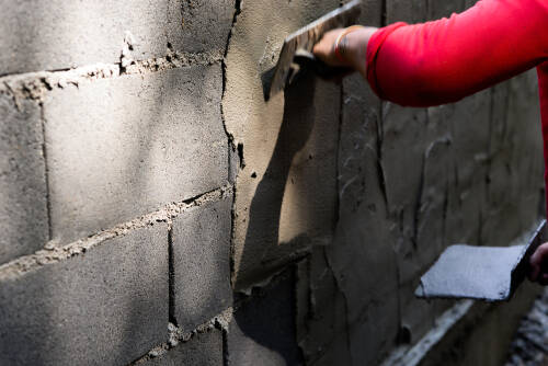Asian plasterer plastering concrete walls