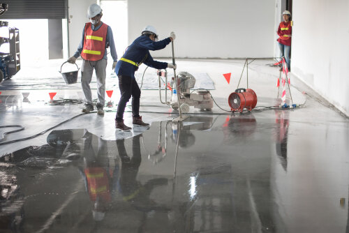 Construction worker painting epoxy flooring or floor hardener